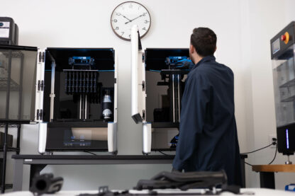 A photo of a technician working next to two Xip Pro 3D printers